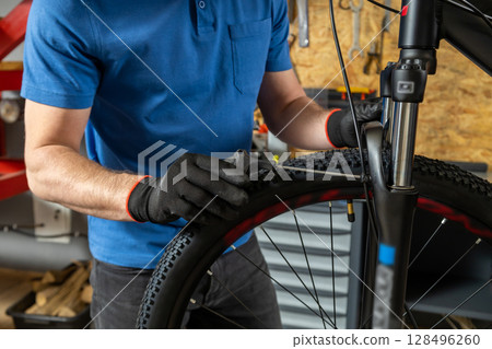Professional man fixing bike carefully in garage Professional man fixing bike carefully in garage 128496260