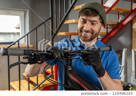 Mechanic repairing bicycle gears in workshop with window on background 128496283