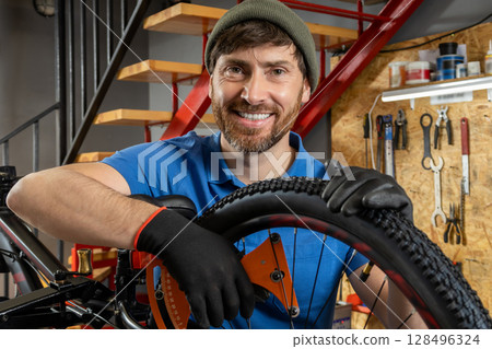 Mechanic repairing bicycle tire in tidy modern workshop Mechanic repairing bicycle tire in tidy modern workshop 128496324