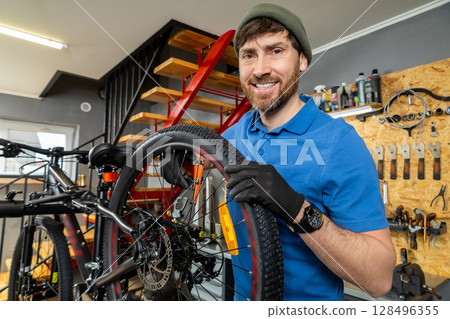 Mechanic repairing bicycle tire in tidy modern workshop Mechanic repairing bicycle tire in tidy modern workshop 128496355