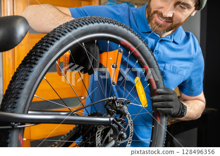 Master fixes bike wheel in organized garage with modern setup Master fixes bike wheel in organized garage with modern setup 128496356