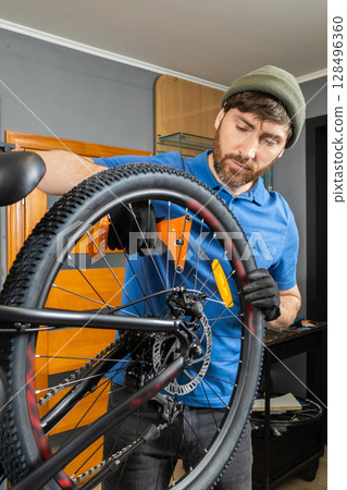 Mechanic repairing bicycle tire in tidy modern workshop 128496360