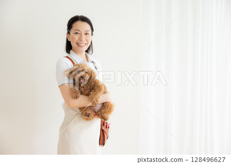 Groomer: Portrait of a groomer holding a toy poodle Groomer: Portrait of a groomer holding a toy poodle 128496627
