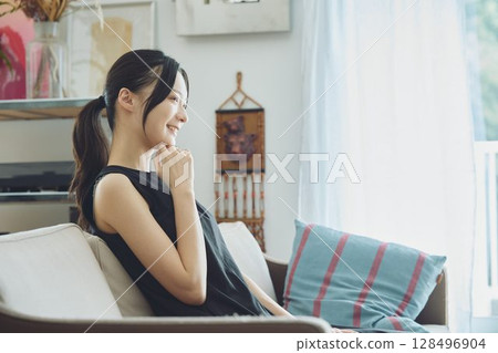 坐在客廳沙發上的女人 坐在客廳沙發上的女人 128496904