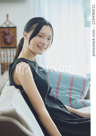 Woman sitting on sofa in living room Woman sitting on sofa in living room 128496912