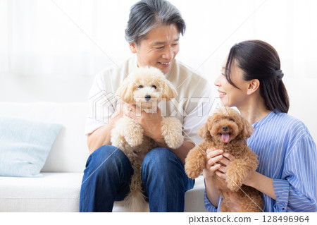 一對中年夫婦在客廳和他們的狗一起玩耍 128496964