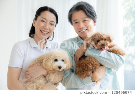 一對中年夫婦在客廳和他們的狗一起玩耍 128496974