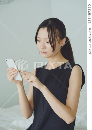 一個在床上使用智能手機的女人 128497230