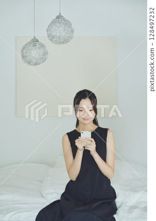 一個在床上使用智能手機的女人 128497232