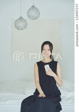 A woman using a smartphone in bed A woman using a smartphone in bed 128497237