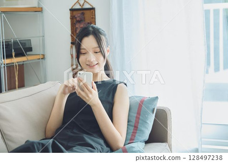 A woman using a smartphone on a sofa A woman using a smartphone on a sofa 128497238