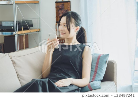 A woman using a smartphone on a sofa 128497241