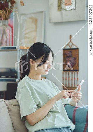 使用智能手機的婦女在沙發 使用智能手機的婦女在沙發 128497265