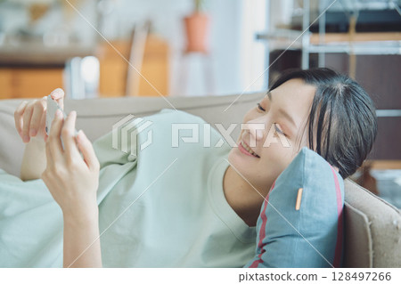 使用智能手機的婦女在沙發 使用智能手機的婦女在沙發 128497266