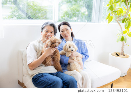 A middle-aged couple spending time with their dog in the living room 128498101