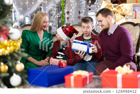 Smiling family celebrating Christmas and giving each other gifts Smiling family celebrating Christmas and giving each other gifts 128498412
