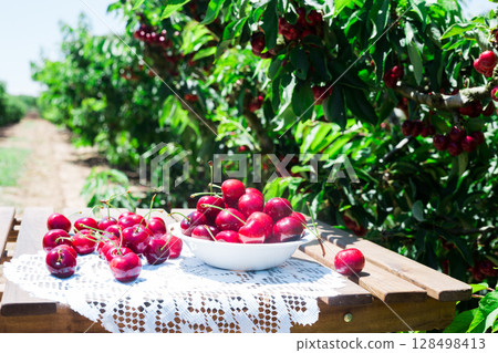 White bowl filled with ripe cherries on table  128498413