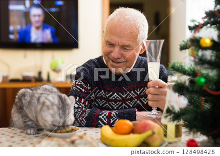 elderly man together with a cat of the Scottish fold cat celebrates new year at festive table elderly man together with a cat of the Scottish fold cat celebrates new year at festive table 128498428