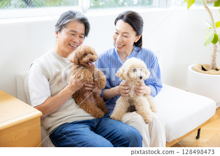 一對中年夫婦在客廳和他們的狗一起玩耍 128498473