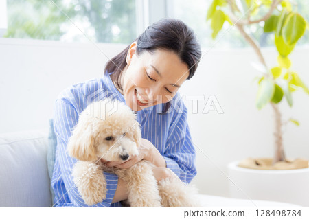A middle-aged woman holding a Bichon Poo 128498784