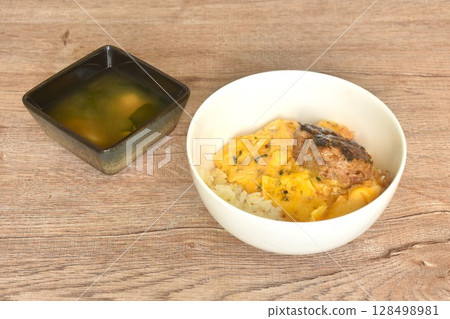 grilled hamburg pork steak and creamy egg omelets topping on rice in bowl with miso or soy sauce soup 128498981