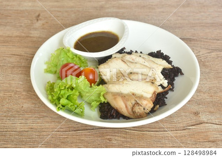 grilled slice chicken black pepper on riceberry with tomato and lettuce on plate dipping Thai spicy tamarind sauce 128498984