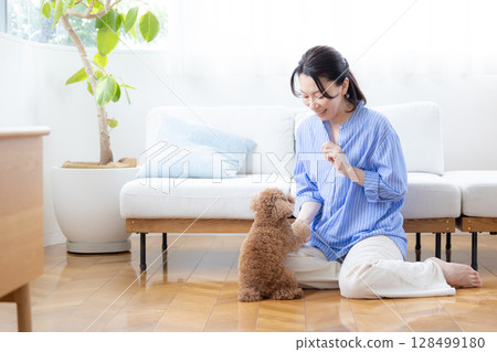 Middle-aged woman playing with a toy poodle 128499180