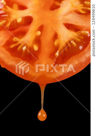 Natural tomato juice dripping from half a fresh tomato, black background Natural tomato juice dripping from half a fresh tomato, black background 128499610