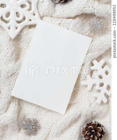 Vertical blank card on white knitted sweater near Christmas decor, winter Holiday mockup 128499952