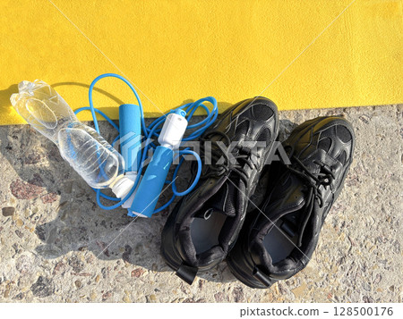 Jump rope, bottle of water, and sneakers on sports mat, top view. Fitness equipment, workout essentials, healthy lifestyle, flat lay composition 128500176