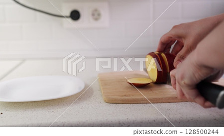 Healthy food prep process, Simple apple cutting scene, Kitchen counter fruit action, Planning daily fruit intake, Knife and apple coordination, Red fruit on wooden board, Clean home kitchen background Healthy food prep process, Simple apple cutting scene, Kitchen counter fruit action, Planning daily fruit intake, Knife and apple coordination, Red fruit on wooden board, Clean home kitchen background 128500244