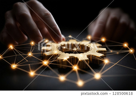 Hands interacting with a golden gear amidst a glowing network of connections 128500618