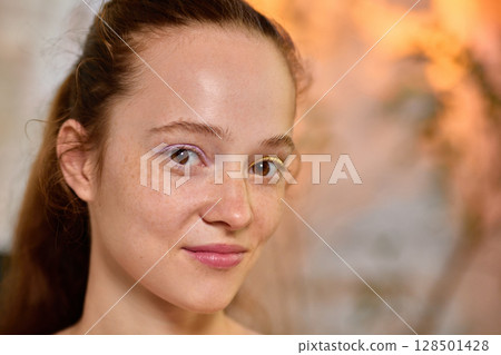 Bold Y2K. Portrait of confident woman with dual-color eyeliner and gentle smile 128501428