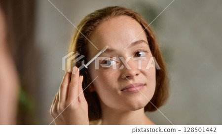 Clean-girl. Close-up portrait of calm woman brushing eyebrows with natural expression Clean-girl. Close-up portrait of calm woman brushing eyebrows with natural expression 128501442