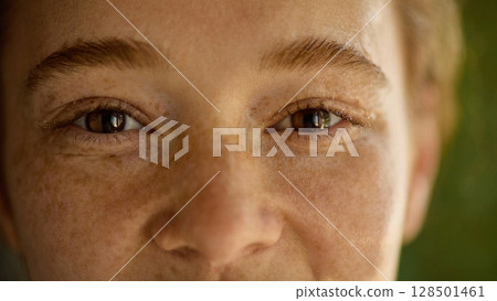 Extreme close-up of smiling freckled woman with joyful eyes and glowing skin Extreme close-up of smiling freckled woman with joyful eyes and glowing skin 128501461