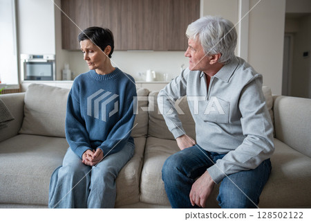 Elderly couple in conflict, husband blaming woman while frail wife fear speaking due to abusive  128502122