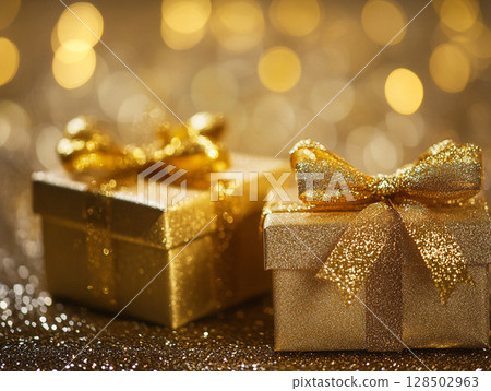 Two sparkling golden gift boxes with bows, set against a shimmering gold bokeh background, evoking celebration and luxury. 128502963