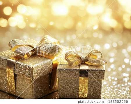 Two sparkling golden gift boxes with bows, set against a shimmering gold bokeh background, evoking celebration and luxury. 128502966