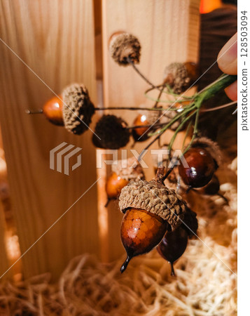 Florist creating autumn decoration with acorns and raffia Florist creating autumn decoration with acorns and raffia 128503094