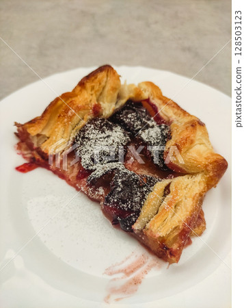 Delicious plum galette with icing sugar on white plate Delicious plum galette with icing sugar on white plate 128503123