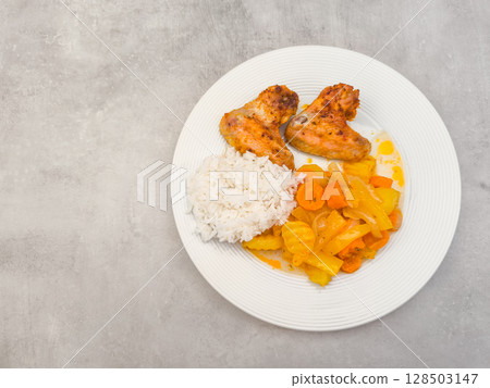 Roasted chicken wings with rice and stewed vegetables on white plate, copy space Roasted chicken wings with rice and stewed vegetables on white plate, copy space 128503147
