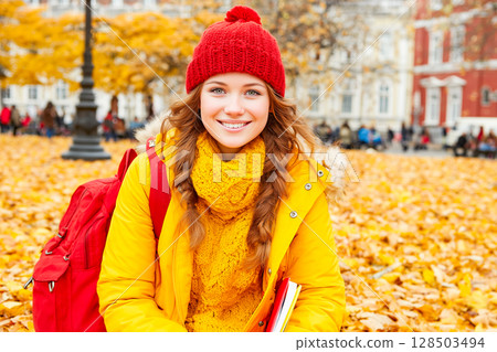 Smiling teenage girl with books in autumn park 128503494