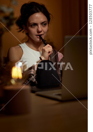 beautiful graphic designer woman with stylus working using digital graphic tablet and laptop in the evening beautiful graphic designer woman with stylus working using digital graphic tablet and laptop in the evening 128503777