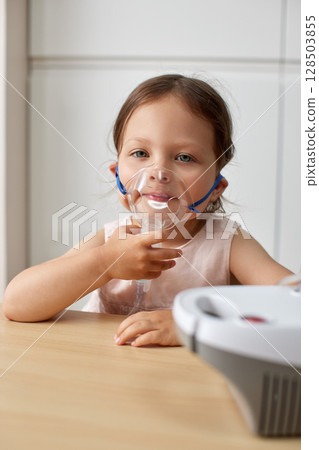 cute little toddler girl inhaling medicine on nebulizer and holding it on her own cute little toddler girl inhaling medicine on nebulizer and holding it on her own 128503855