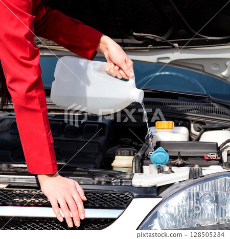 Cropped image of woman pouring windshield washer fluid into car Cropped image of woman pouring windshield washer fluid into car 128505284