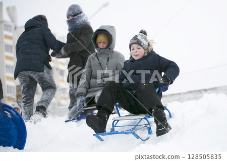 A group of children sledding on a winter day. A group of children sledding on a winter day. 128505835
