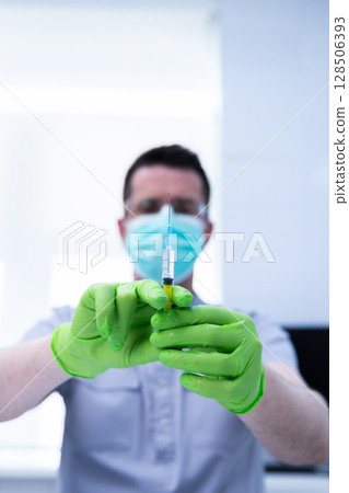 Healthcare Professional Prepared for Vaccination with Syringe and Green Gloves in a Modern Medical Setting Focused on Patient Care and Health Promotion Healthcare Professional Prepared for Vaccination with Syringe and Green Gloves in a Modern Medical Setting Focused on Patient Care and Health Promotion 128506393