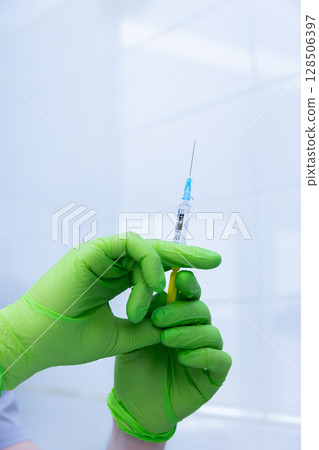 Carefully Preparing a Syringe Amidst a Clean Environment: Ensuring Safety and Hygiene During Medical Procedures with Sterile Equipment and Protective Gear 128506397
