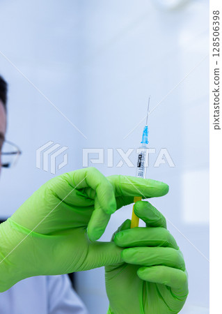 Healthcare Professional Preparing a Syringe with Vaccine or Medication in a Clinical Setting, Showcasing Precise and Careful Handling of Medical Equipment Healthcare Professional Preparing a Syringe with Vaccine or Medication in a Clinical Setting, Showcasing Precise and Careful Handling of Medical Equipment 128506398