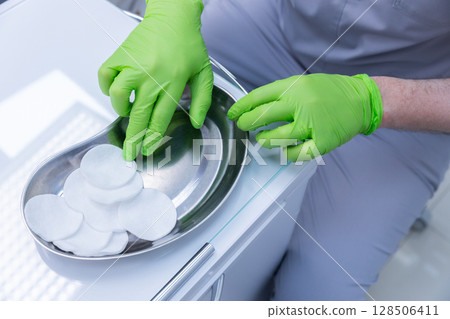 Medical Professional Preparing Sterile Cotton Pads in a Clinical Environment, Emphasizing Hygiene and Safety Procedures for Patient Care and Treatment. Medical Professional Preparing Sterile Cotton Pads in a Clinical Environment, Emphasizing Hygiene and Safety Procedures for Patient Care and Treatment. 128506411